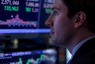 Trader-staring-at-TV-screen-displaying-oil-price-quotes-financial-data-and-charts-on-monitor-trading-floor-or-office-environment-focused-professional-watching-market-prices-stock-market-